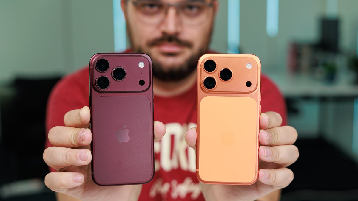 Man holding two iPhone models side by side in burgundy and orange colors