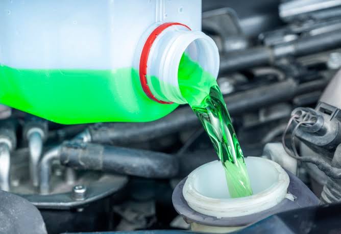 Pouring green antifreeze coolant into a car cooling system reservoir